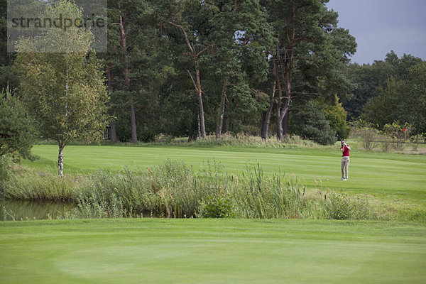 Eine Golferin  die in der Ferne abschlägt.