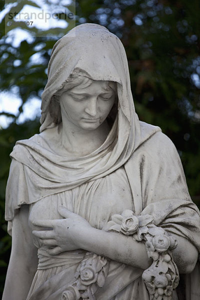 Eine Statue einer gekleideten Frau  die einen Kranz hält.