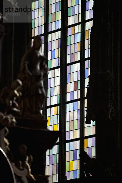 Ein Buntglasfenster im Rücken der begehrten Statuen  Fokus auf das Fenster