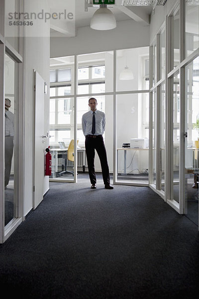 Ein Geschäftsmann steht am Ende eines Korridors.