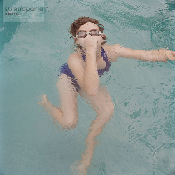 Ein Mädchen hält die Nase unter Wasser.
