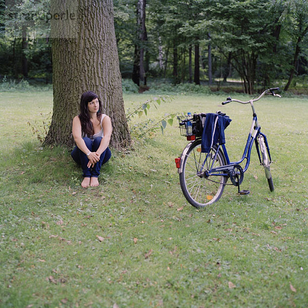 Eine Frau entspannt sich unter einem Baum neben einem Fahrrad