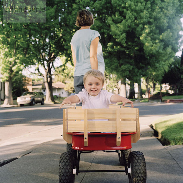 Eine Mutter  die ihren kleinen Sohn in einem Wagen zieht  konzentriert sich auf den Jungen.