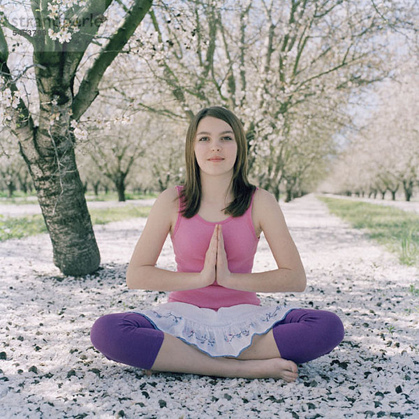 Ein Mädchen  das Yoga in der Lotusstellung praktiziert.