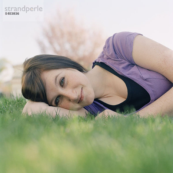 Eine junge Frau  die im Gras liegt.