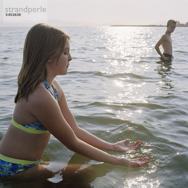 Ein Teenager-Mädchen  das auf dem Wasser schaufelt  während es im Meer watet.