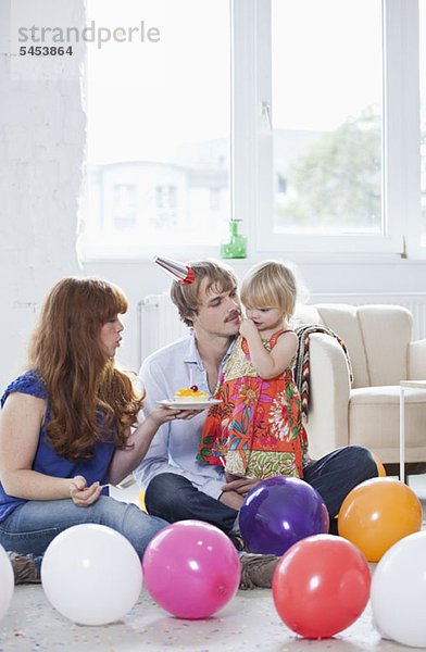 Zwei junge Eltern feiern mit ihr den Geburtstag ihrer Tochter.