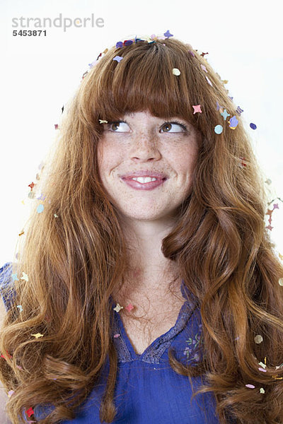 Eine lächelnde junge Frau mit Konfetti im Haar