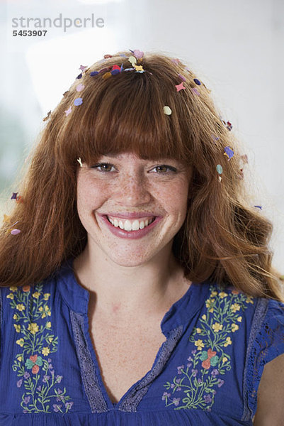 Eine glückliche junge Frau mit Konfetti im Haar