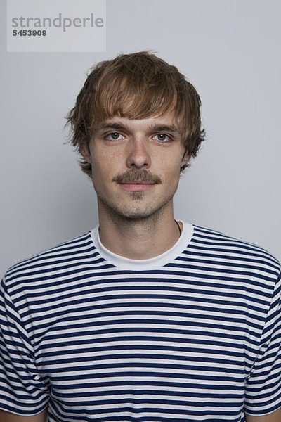 Ein junger Mann mit Schnurrbart im gestreiften T-Shirt