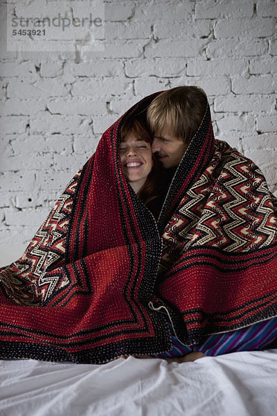 Ein junges glückliches Paar in eine Decke gewickelt.