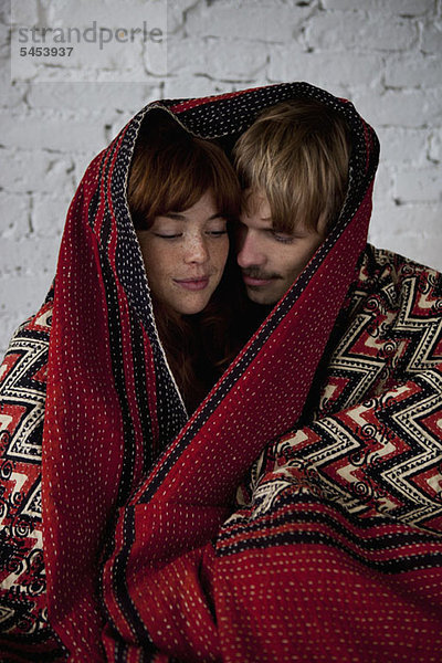Ein junges  ruhiges Paar in eine Decke gehüllt.
