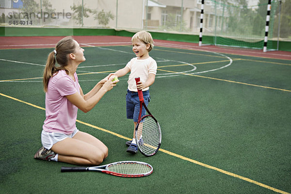 Eine Mutter und ein Sohn haben Spaß auf dem Tennisplatz.