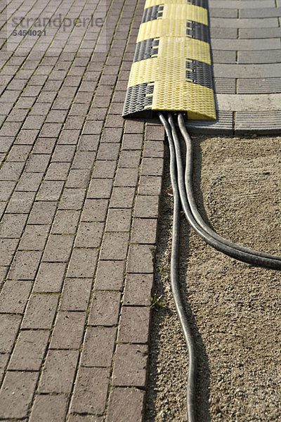 Kabel  die von einer Geschwindigkeitsbegrenzung auf einer Kopfsteinpflasterstraße kommen.
