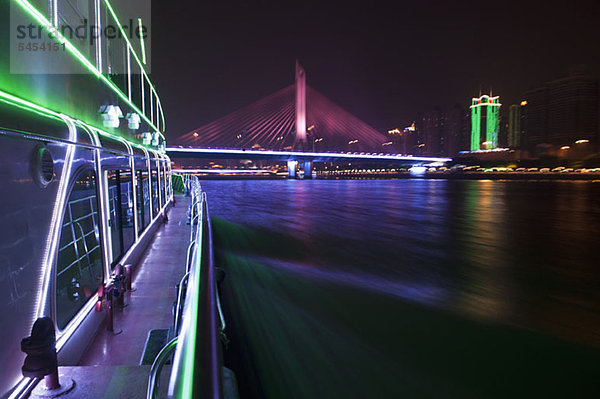 Yacht auf dem Pearl River in Hongkong und beleuchtete Haiyin Bridge im Hintergrund