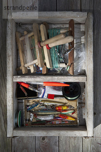 Schachtel mit Angelausrüstung auf dem Hintergrund von Holzpaneelen