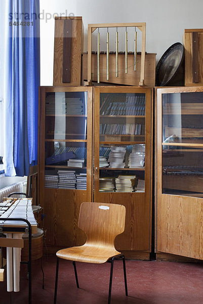 Schulmusikraum mit Instrumenten  Musikbüchern und einem leeren Stuhl