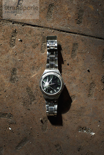 Gebrochene Armbanduhr auf Beton