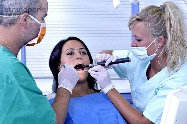 Patientin bei Zahnbehandlung mit Zahnarzt und Helferin
