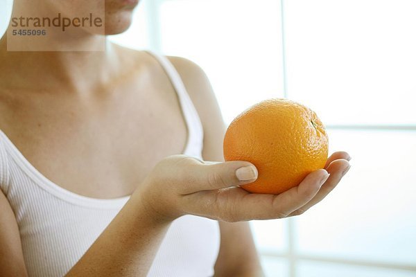 Frau hält eine Orange