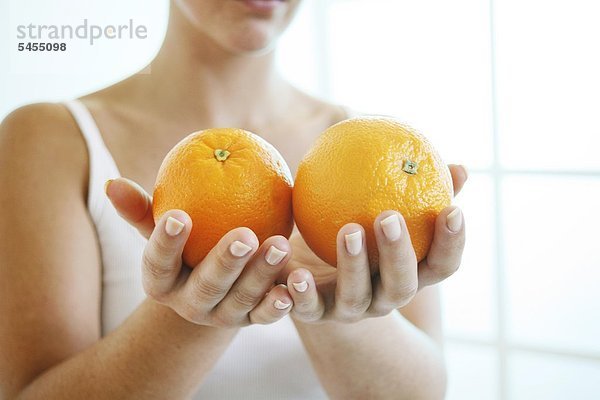 Frau hält zwei Orangen