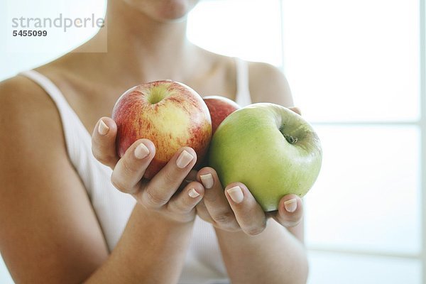 Frau hält drei Äpfel