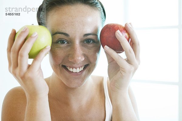 Lächelnde Frau hält zwei Äpfel  Portrait