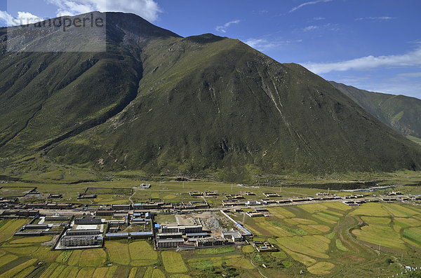 Tibetisches Dorf mit tibetischen Bauernhäusern vor Gebirgszug und Gerstenfeldern  Drigung Till  Meldro Gongkar  Tibet  China  Asien