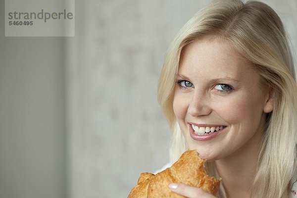 Junge Frau isst ein Croissant