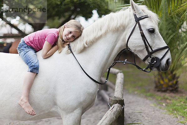 Lächelndes Mädchen beim Reiten im Hof