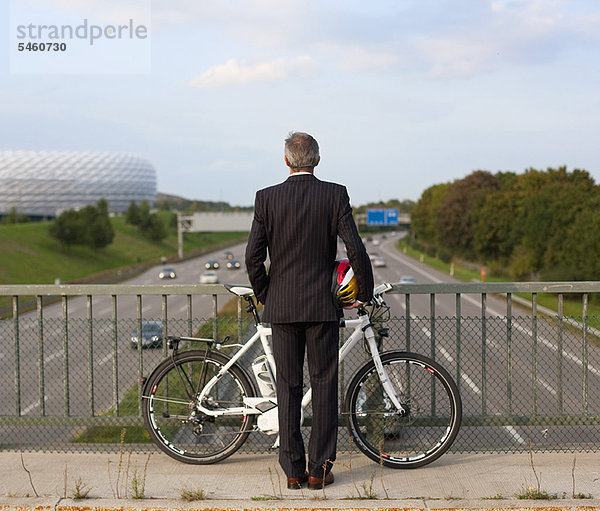 Geschäftsmann mit Fahrrad auf der Brücke