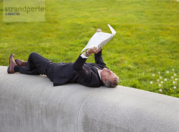 Geschäftsmann beim Zeitungslesen im Park