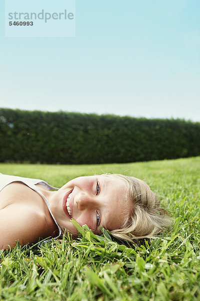 Lächelndes Mädchen im Gras liegend