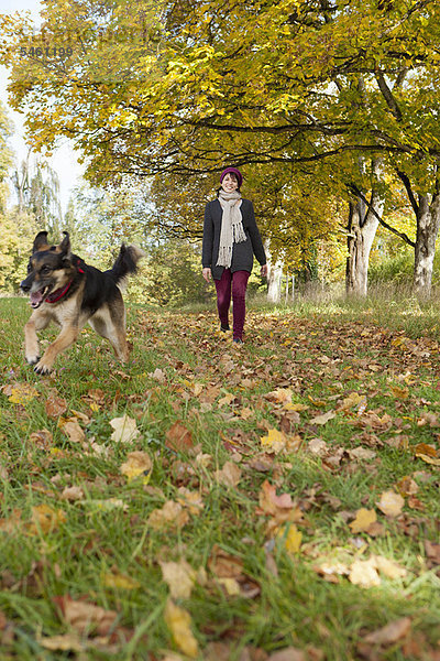 Lächelnde Frau spazieren gehender Hund im Park