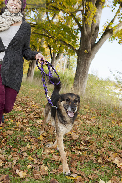 Lächelnde Frau spazieren gehender Hund im Park