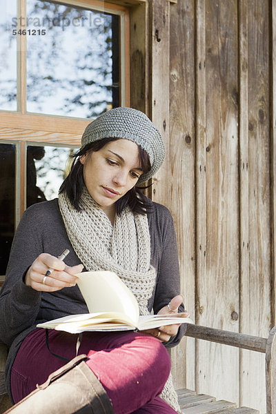 Frau schreibt im Notizbuch auf der Veranda