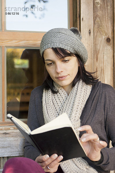 Frau liest Buch auf der Veranda