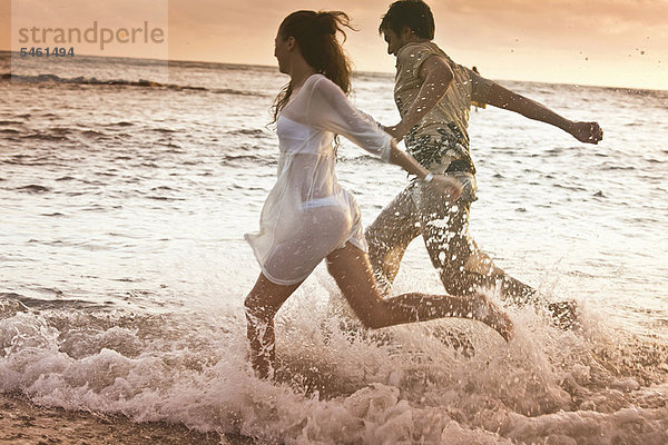 Paar läuft in Wellen am Strand