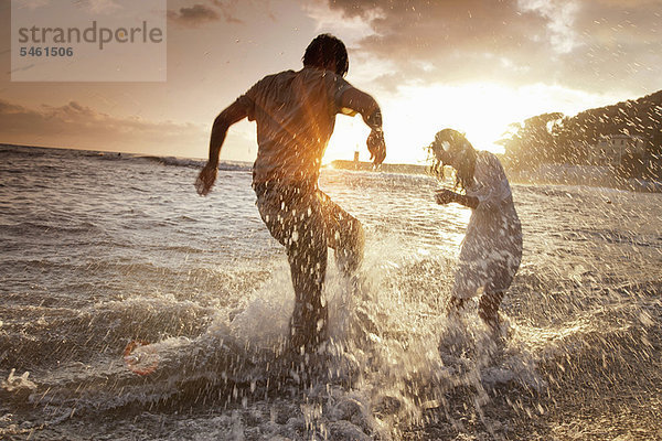 Paar spielt in Wellen am Strand