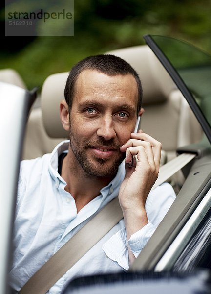 Portrait of Man in convertible Car talking on phone