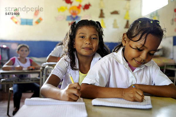 Zwei Mädchen teilen sich eine Schulbank  Schule in Las Mesitas  Bajo Lempa  El Salvador  Zentralamerika  Lateinamerika