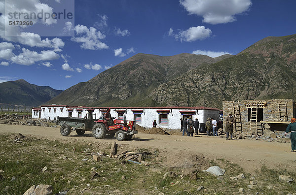 Tibetische Handwerker mit Traktor beim Bau eines traditionellen tibetischen Gebäudes  Pundo  Reting  Himalaya  Lhundrup County  Zentraltibet  Tibet  China