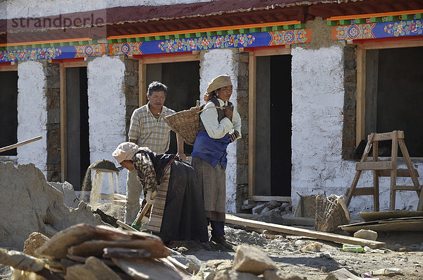 Tibetische Handwerker  Frauen in Tracht und Männer  beim Bau eines traditionellen tibetischen Gebäudes  Pundo  Reting  Himalaya  Bezirk Lhundrup  Zentraltibet  Tibet  China  Asien
