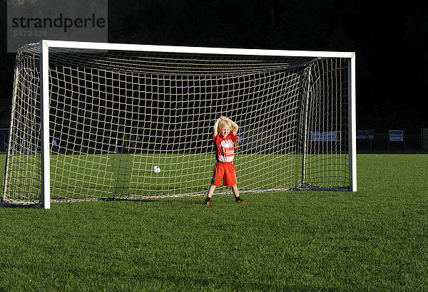 Fünfjähriger Junge in FC Bayern München Dress steht gelangweilt im Fußballtor