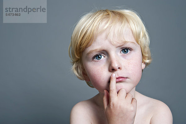 Fünfjähriger Junge hält nachdenklich den Finger vor den Mund  Portrait