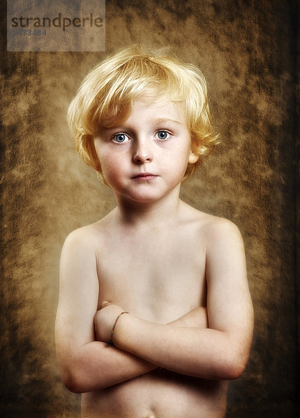 Fünfjähriger Junge mit freiem Oberkörper und verschränkten Armen  ernster Blick  Portrait