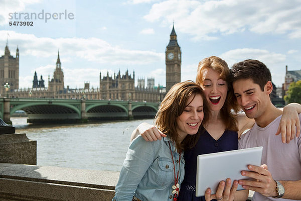 Freunde  die zusammen ein digitales Tablett in London betrachten
