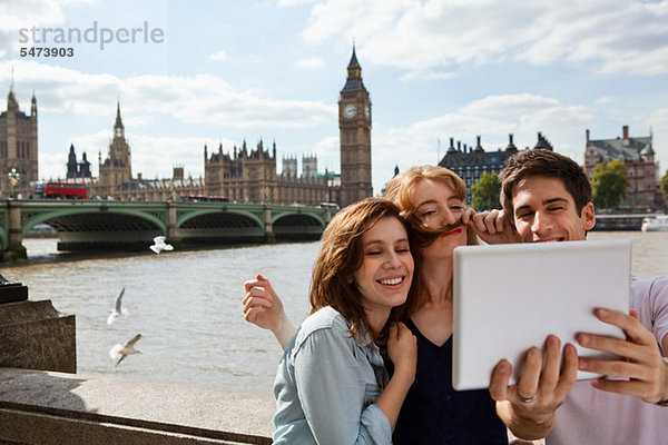 Freunde  die ein digitales Tablett in der Londoner Innenstadt benutzen
