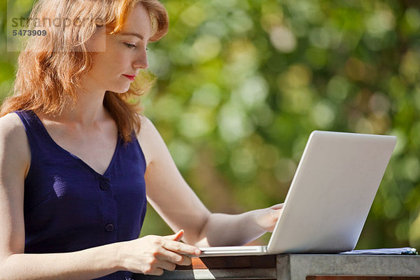 Junge Frau mit einem Laptop außerhalb