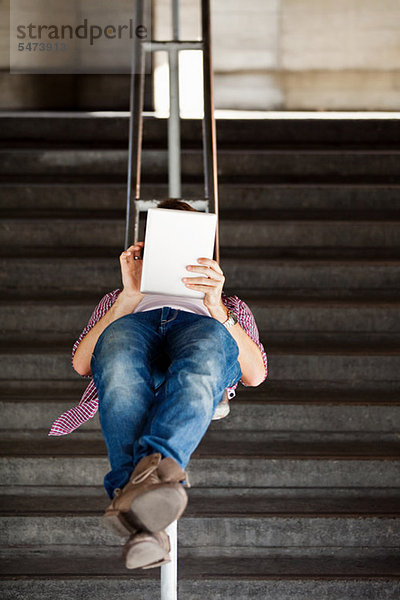 Ein junger Mann auf dem Rücken liegend eines digitalen Tabletts